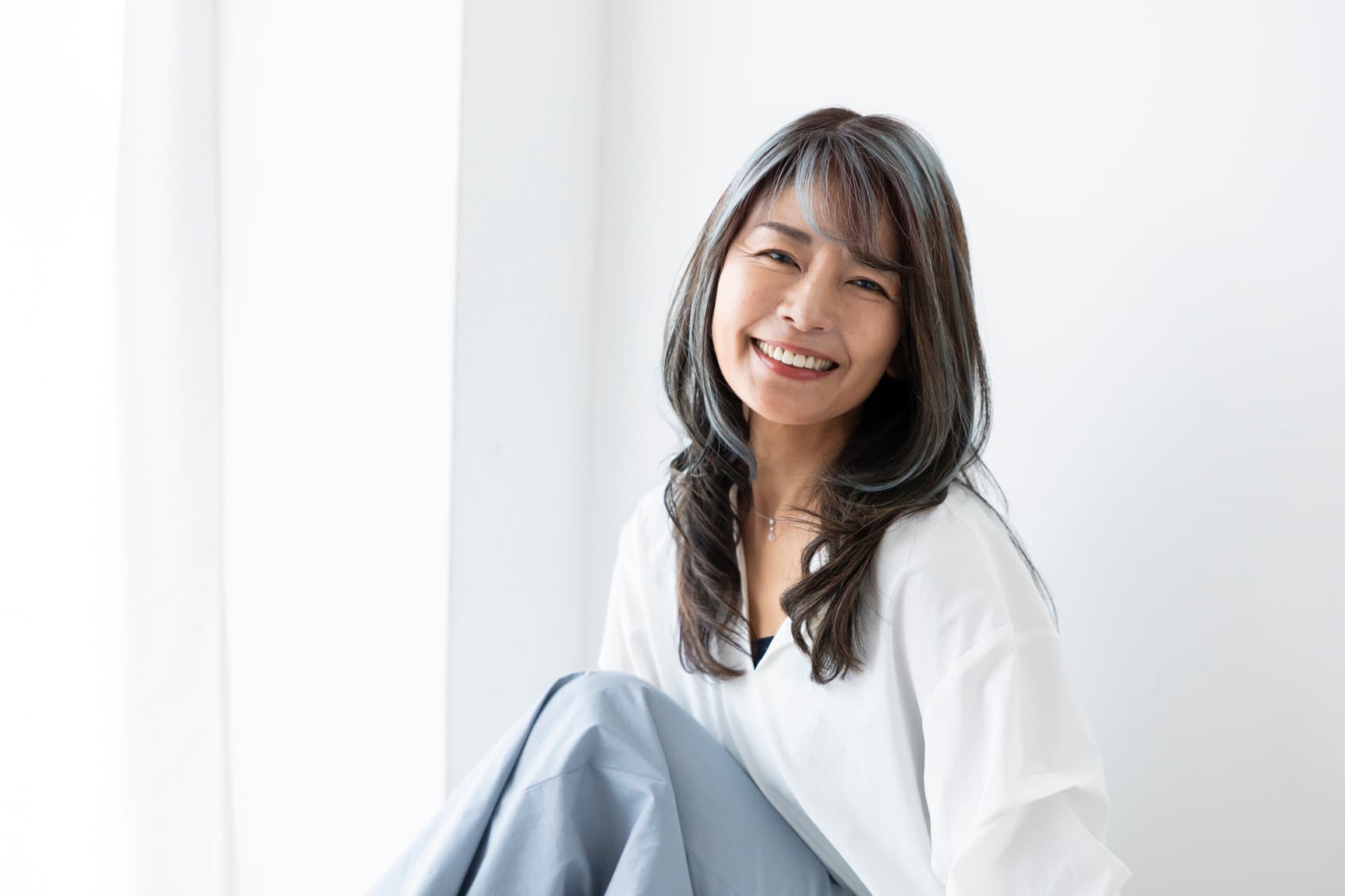 秋の並木道で微笑むスノーブルー着用の女性